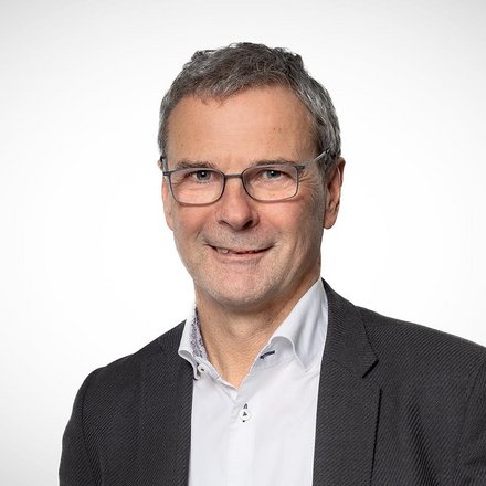 Porträt eines Mannes mit Brille vor neutralem Hintergrund