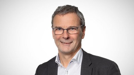 Porträt eines Mannes mit Brille vor neutralem Hintergrund