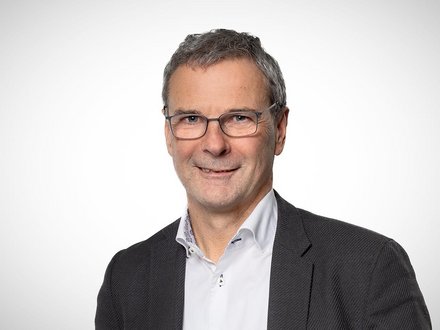 Porträt eines Mannes mit Brille vor neutralem Hintergrund