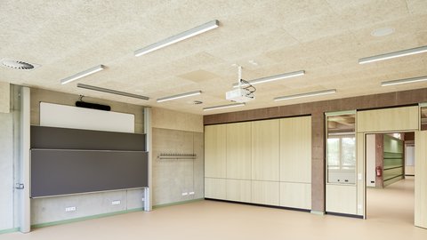 Leerer Klassenraum mit großen Schultafeln, Holzvertäfelung und Deckenbeleuchtung