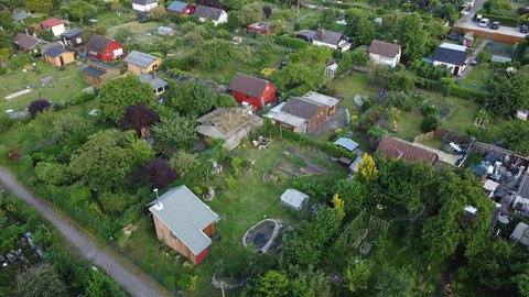 Luftaufnahme einer Kleingartenanlage mit kleinen Gartenhäusern, Beeten und vielen Bäumen.