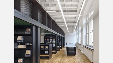 Ein moderner, großzügiger Raum mit schwarzen Regalen, Holzfußboden und Reihen von Materialproben.