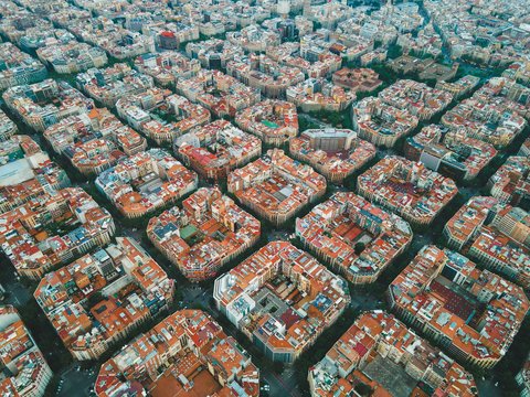 "Luftaufnahme einer dicht bebauten europäischen Stadt mit Wohnblöcken. Ein breiter grüner Grünzug oder Park verläuft als durchgehende Schneise durch die Stadt. Gebäude mit unterschiedlichen Fassaden und Grünanlagen prägen das Stadtbild. Eine Demonstration urbaner Grünflächenvernetzung."