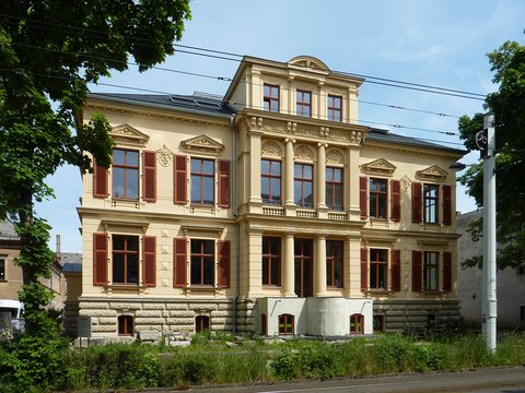 Historische Villa mit reich verzierter Fassade und braunen Fensterläden