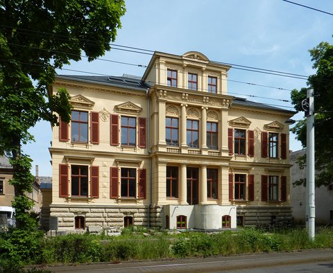 Historische Villa mit reich verzierter Fassade und braunen Fensterläden