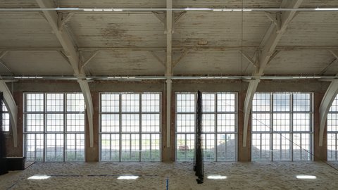 Große, helle Halle mit hohen Fenstern und Sandboden