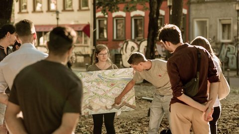 Gruppe von Menschen betrachtet gemeinsam einen großen Stadtplan im öffentlichen Raum von Saarbrücken.