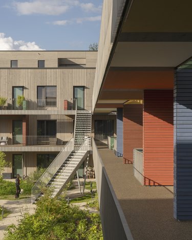 Farbenfrohe Fassaden und Balkone einer modernen Wohnanlage, mit einer Person auf der Terrasse.