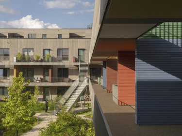 Farbenfrohe Fassaden und Balkone einer modernen Wohnanlage, mit einer Person auf der Terrasse.