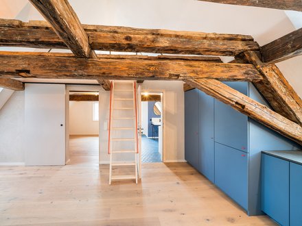 Innenraum mit Holzbalken und Leiter in der Mitte des Raumes.