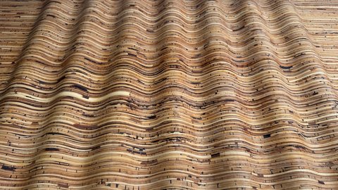 Wellenförmig profilierte Holzoberfläche aus vielen schmalen Lamellen; lebhaftes Linienmuster.