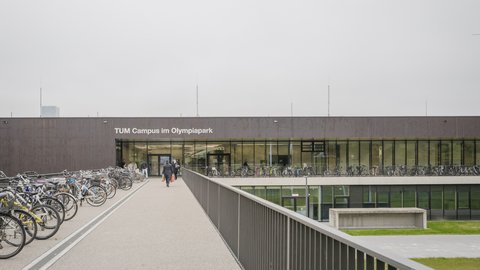 Campusgebäude mit Fahrradstellplätzen und Zugang über eine erhöhte Promenade.