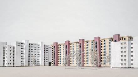 Architekturmodell, Siedlung Alt: Modellfoto mehrerer Plattenbau‑Riegel mit kleinen Bäumen; vorn weißliche Blöcke, dahinter farbige Hochhäuser, neutraler Hintergrund.