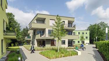 Ein grünes Wohnhaus mit Grünanlagen herum.