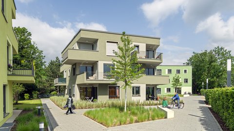 Ein grünes Wohnhaus mit Grünanlagen herum.