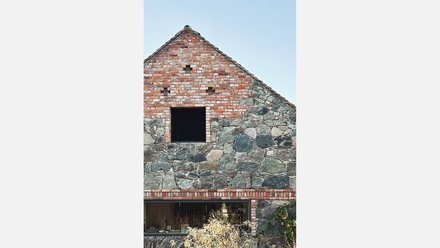 Nordfassade: Feldsteingiebel mit Backsteineinfassungen; oben kleines quadratisches Öffnungsfeld, unten langes Panoramafenster.