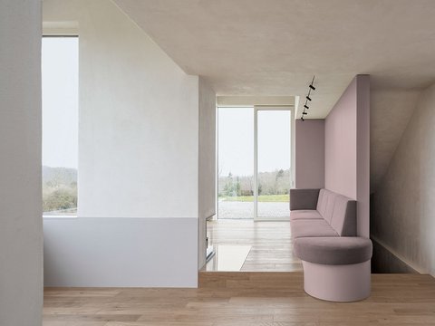 Moderner Innenraum mit hellen Wänden, Holzfußboden, eingebautem Kamin und langem, gepolstertem Sitzbankelement an der Wand