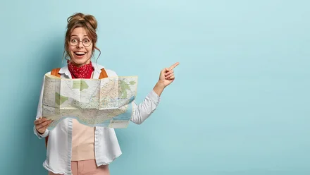 Junge Frau mit Landkarte freut sich und zeigt zur Seite