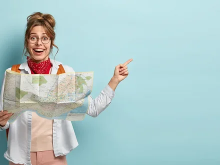Junge Frau mit Landkarte freut sich und zeigt zur Seite