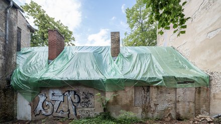 Sanierungsbedürftiges Gärtnerhaus mit Plastikplane auf dem Dach