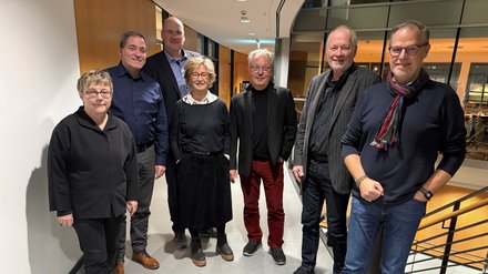 Personengruppe von 7 Personen steht in einem Gang mit Blick zur Kamera.