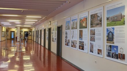 Flurartige Ausstellung mit großformatigen Architekturtafeln zu Holzbauprojekten an den Wänden.