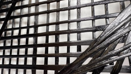 Nahaufnahme eines schwarzen, glänzenden, geflochtenen Materials mit rechteckigem Gittermuster