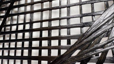 Nahaufnahme eines schwarzen, glänzenden, geflochtenen Materials mit rechteckigem Gittermuster
