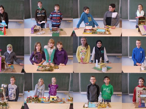 "Ein Mosaik aus zwölf Porträtfotos. Jedes Bild zeigt ein oder zwei Schüler, die stolz vor einer Schultafel stehen und ihre selbstgebastelten Architektur-Modelle aus Pappe, Papier und Naturmaterialien präsentieren. Die Modelle sind sehr unterschiedlich gestaltet, von farbenfrohen Häusern bis hin zu Burgruinen."