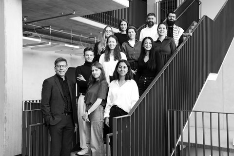 Gruppe von Architekt:innen und Mitarbeitenden, die gemeinsam auf einer Treppe in einem modernen Bürogebäude stehen.