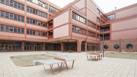 Moderner mehrstöckiger Gebäudekomplex mit rechteckigen Fenstern und Innenhof mit Tischtennisplatten