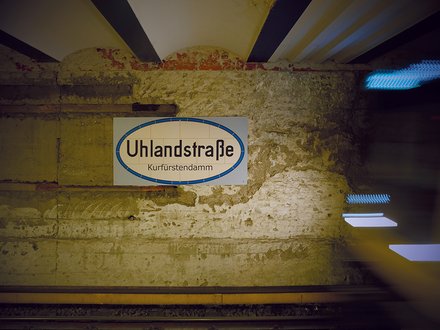 U-Bahnhofsschild „Uhlandstraße“ an einer historischen Wand.