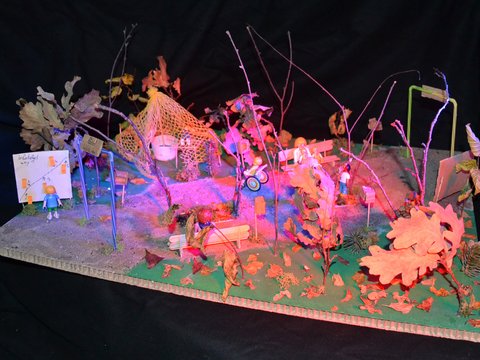 Modell einer fantasievollen Spiellandschaft mit Bänken, Bäumen und Figuren.