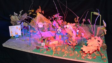 Modell einer fantasievollen Spiellandschaft mit Bänken, Bäumen und Figuren.