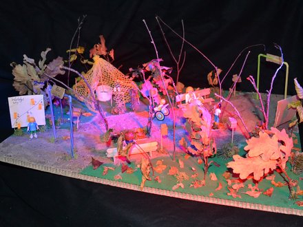 Modell einer fantasievollen Spiellandschaft mit Bänken, Bäumen und Figuren.