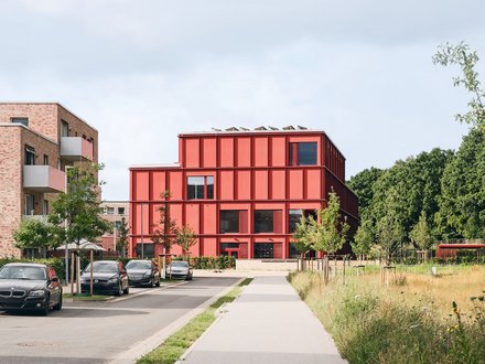 Bild einer Straße, an deren Ende sich eine moderne Grundschule befindet