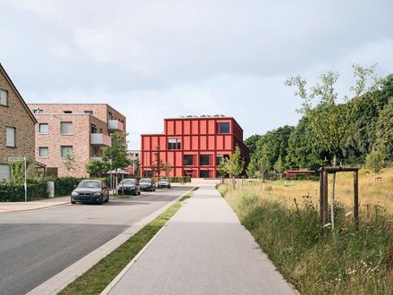 Bild einer Straße, an deren Ende sich eine moderne Grundschule befindet