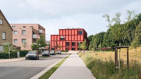 Bild einer Straße, an deren Ende sich eine moderne Grundschule befindet