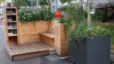 Parklet aus Holz mit öffentlichem Bücherschrank als temporäre Erweiterung des Straßenraums.