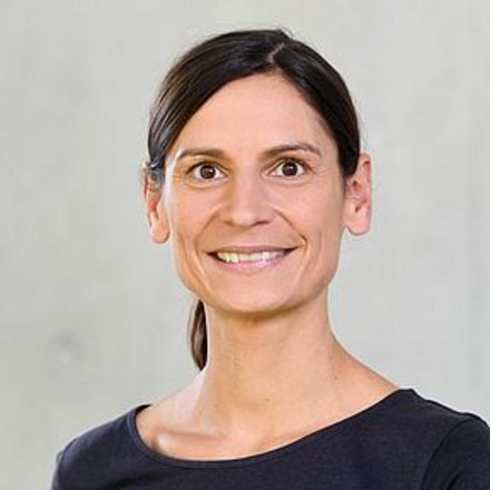 Ein Porträt zeigt eine einzelne erwachsene Person vor neutralem Hintergrund, frontal zur Kamera ausgerichtet und ruhig lächelnd, wodurch das Bild eine professionelle Darstellung vermittelt und für Autorenschaft, fachliche Kompetenz oder eine persönliche Stimme innerhalb eines kulturellen oder fachlichen Kontextes steht.