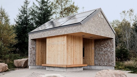 Kleines Gebäude mit Holzverkleidung und Schindeldach in natürlicher Umgebung mit großen Steinen davor