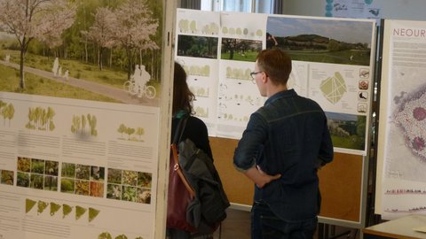 Ausstellung mit Landschaftsarchitektur-Postern, vor denen zwei Personen stehen und die Inhalte betrachten.