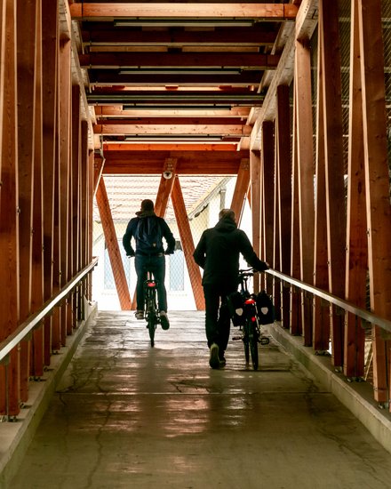 Innenansicht eines Fahrradparkhauses; zwei Personen verlassen das Fahrradparkhaus mit ihren Fahrrädern auf der Rampe 