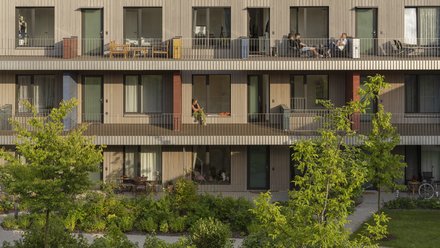  Ansicht eines modernen, mehrstöckigen Holzgebäudes mit begrünten Terrassen und Balkonen.