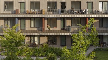  Ansicht eines modernen, mehrstöckigen Holzgebäudes mit begrünten Terrassen und Balkonen.