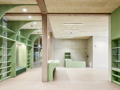 Leerer Raum mit grünen Regalen und Theken aus Holz sowie sichtbaren Betonstützen und -wänden