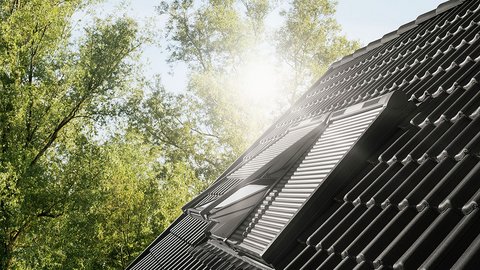 „Ein modernes Dachfenster auf einem dunklen Ziegeldach, angestrahlt von hellem Sonnenlicht vor dem Hintergrund grüner Baumkronen.“