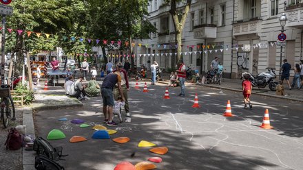 Autofreie Spielstrasse mit Passanten und Kindern, die auf der Straße spielen.