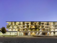 Modernes mehrstöckiges Schulgebäude mit großen Fenstern und begrünten Balkonen bei Dämmerung
