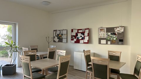 Ausstellung von Schülerarbeiten in einem Gemeindesaal mit Stellwänden und gerahmten Projektpräsentationen.